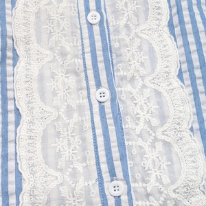 Detailed macro view of blue striped fabric with elegant white lace trim and resin buttons
