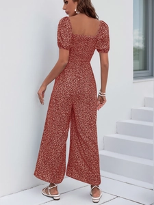 Detail of reddish-brown floral romper featuring square neck and puff sleeves against white wall