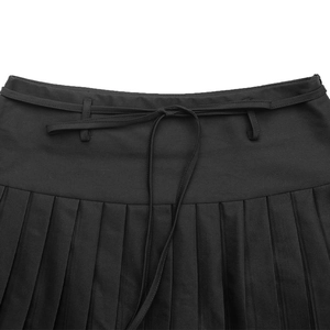 Detail of black pleated skirt featuring high-waist drawstring ties and crisp knife pleats