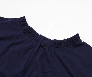 Détail de la robe en maille bleu marine avec col à volants, bouton et découpe goutte