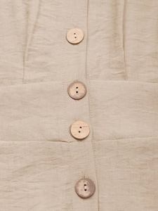 Close-up of wooden buttons on a beige textured linen summer jumpsuit for women