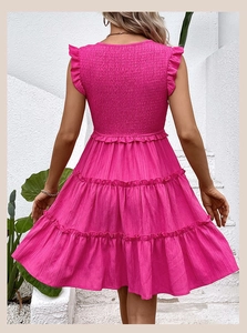 Detail view of the smocked bodice and layered ruffle hem on a rose pink summer dress