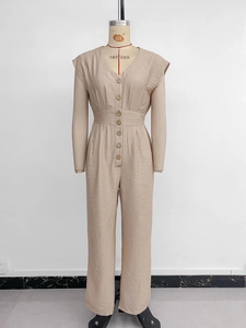 Macro shot of V-neck button detailing and textured fabric on beige jumpsuit