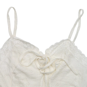 Detail of white knit camisole featuring delicate lace trim and a central bow ribbon