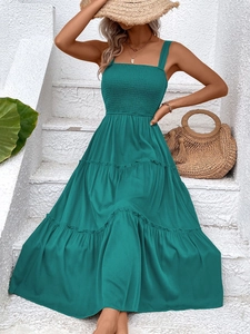 Close-up of the smocked bodice and tiered skirt on a teal summer vacation dress