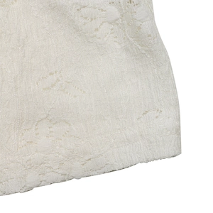 Macro shot of intricate floral lace knit texture and premium crochet detail on white top