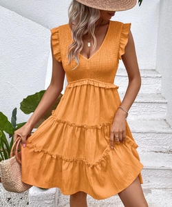 Detail of vibrant orange V-neck tiered dress with ruffle sleeves and pleated waist