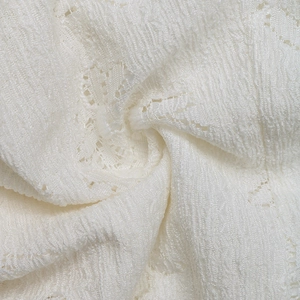 Close-up of white knit jacquard fabric with delicate lace texture and wavy patterns