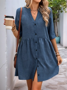Close-up of a blue V-neck button-up dress with rolled sleeves and textured fabric
