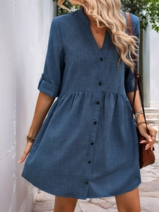 Detail of blue V-neck midi dress with black buttons, rolled mid-sleeves and waist pleats