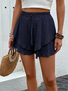 Detail of navy textured cotton shorts showing elastic waist drawstring and layered hem design