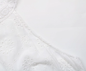 Détail de la broderie anglaise florale blanche et du col en dentelle crochetée ondulée