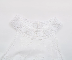 Détail de robe blanche dos nu avec dentelle florale au cou et broderie anglaise