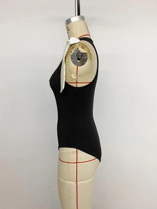 Détail d'un body noir sans manches avec nœud papillon blanc sur un mannequin de couture