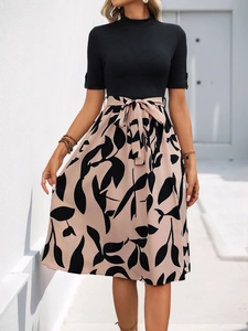 Détail du nœud à la taille sur une robe midi contrastée en maille noire et jupe fleurie