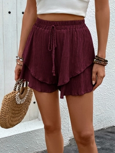 Detail of high-waisted burgundy layered ruffle shorts with textured fabric and drawstring