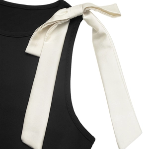 Détail d'un body noir avec des bretelles élégantes en satin crème nouées en nœud