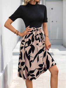 Détail d'une robe effet deux-pièces avec haut côtelé noir et jupe trapèze fleurie à nouer