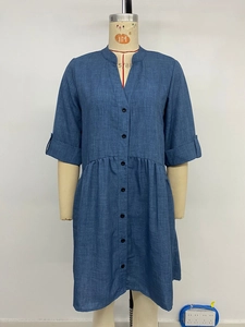 Detail of blue V-neck shirt dress featuring black buttons and pleated waist seam