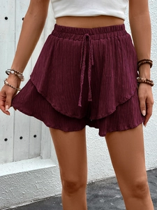 Close-up of wine red tiered shorts featuring a smocked elastic waist and drawstring detail
