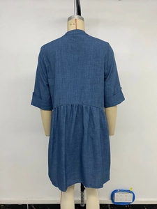 Detail view of the back of a blue linen-textured shirt dress with pleated waist and cuffs