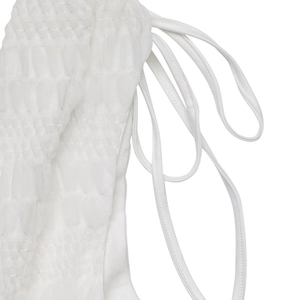 Detailed macro view of white smocked fabric texture and side drawstring ties on the dress