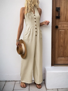Detail of beige halter V-neck jumpsuit showing fabric texture and tortoiseshell buttons