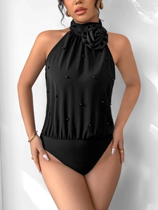 Detail of black halter bodysuit featuring a 3D floral rose and delicate pearl accents