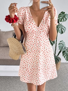 Détail d'une robe d'été blanche à fleurs rouges, col en V et manches bouffantes