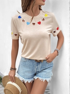 Détails des découpes en forme de cœur et broderies colorées sur le t-shirt beige femme