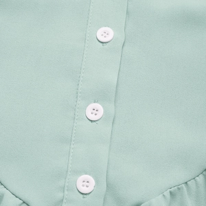 Détail de la robe sans manches vert menthe avec boutons blancs et ourlet plissé