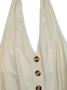 Close-up of beige halter jumpsuit featuring vertical crinkle texture and brown buttons