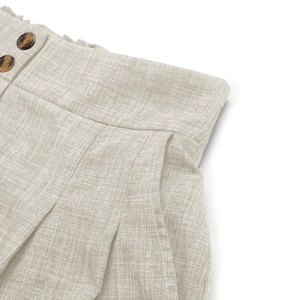 Detail von High-Waist-Leinenshorts mit Rüschenbund und dekorativen Schildpatt-Knöpfen