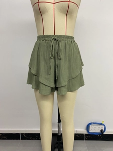 Detail of army green ruffled shorts featuring textured fabric and woven drawstring waist