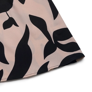 Vue détaillée du tissu rose avec motifs de feuilles noires et coutures fines sur la robe