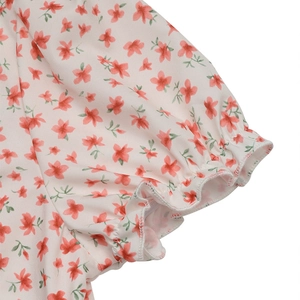 Détail de la manche bouffante fleurie avec poignet volanté sur une robe d'été blanc cassé