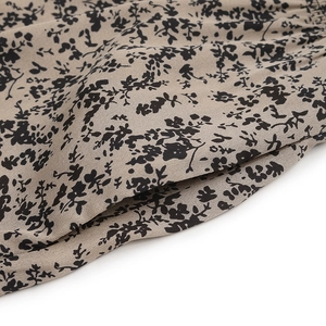 Close-up of khaki floral print fabric texture with intricate stitching and black dot patterns