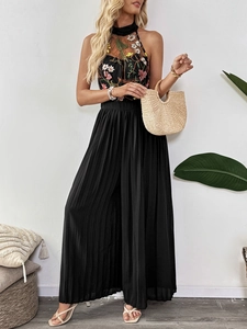 Detail of floral embroidery on black halter neck pleated jumpsuit with wide leg design