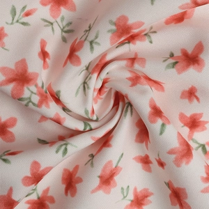 Vue détaillée du tissu floral doux avec base rose et motifs de fleurs rouges