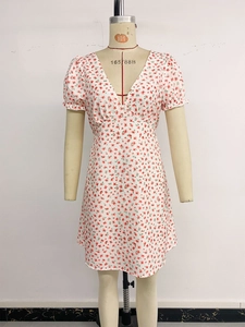 Détail d'une robe fleurie blanche à col en V avec imprimés rouges et manches bouffantes
