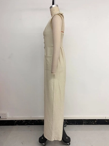 Detail of beige sleeveless jumpsuit featuring a buttoned front and elastic smocked back