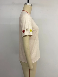 Détail de la broderie en cœur et du design ajouré sur la manche du t-shirt en coton