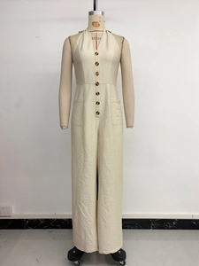 Detail view of beige halter V-neck jumpsuit with button closure and large utility pockets