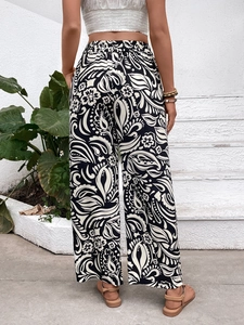 Detail of high waisted wide leg trousers featuring a black and white paisley floral print