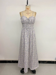 Détail d'une robe longue fleurie montrant la taille smockée et les nœuds réglables