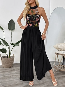 Close-up of intricate floral embroidery on halter neck lace jumpsuit with pleated pants