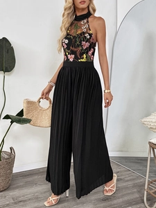 Detail of floral embroidery on mesh halter neck and pleated wide-leg jumpsuit fabric