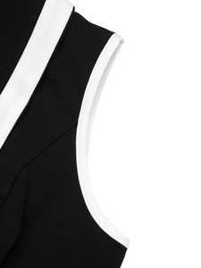 Detail of black dress featuring high-contrast white piping and premium knitted texture