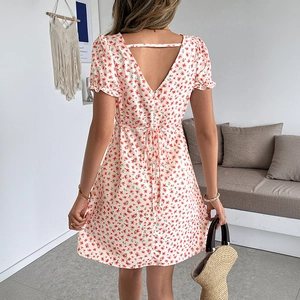 Robe mini fleurie à col en V avec dos nu et ceinture, portée dans un décor intérieur