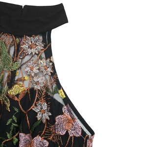 Close-up of floral embroidery on black mesh neckline of the sleeveless halter romper
